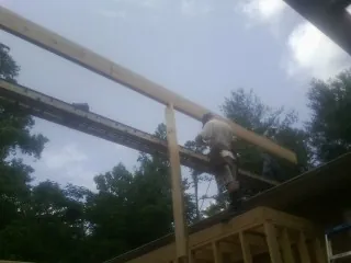 Carpenter setting a ridge beam over a new addition frame — Ice Dam Removal by Roofing Brothers in Nederland