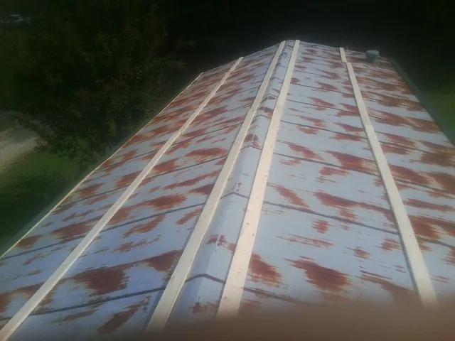 Rusted metal roof panels with new wood purlins before replacement — Storm Damage Roof Repair in Nederland by Roofing Brothers