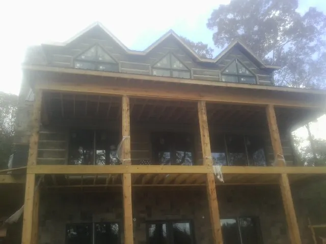 Dormers and porch framing on a large log home under construction — Roof Coating work by our crew in Nederland