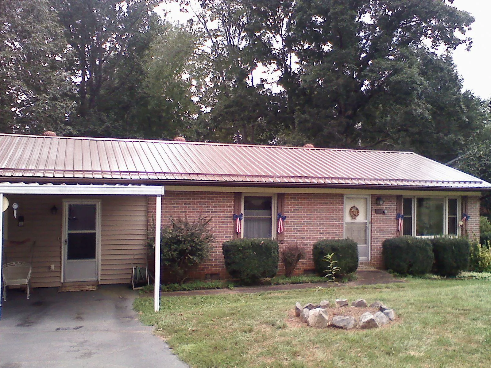 Bronze metal roof and carport on a brick ranch home — Roof Repair work by our crew in Nederland